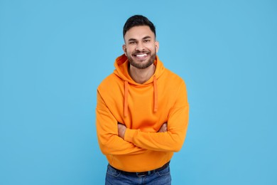 Handsome young man laughing on light blue background