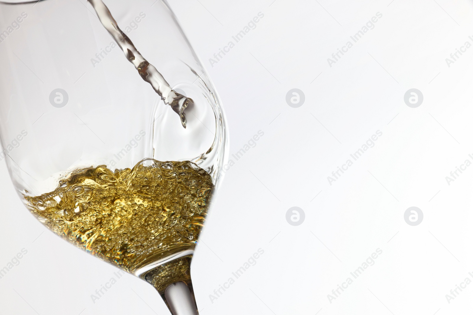 Photo of Pouring tasty aromatic wine in glass on white background, closeup. Space for text