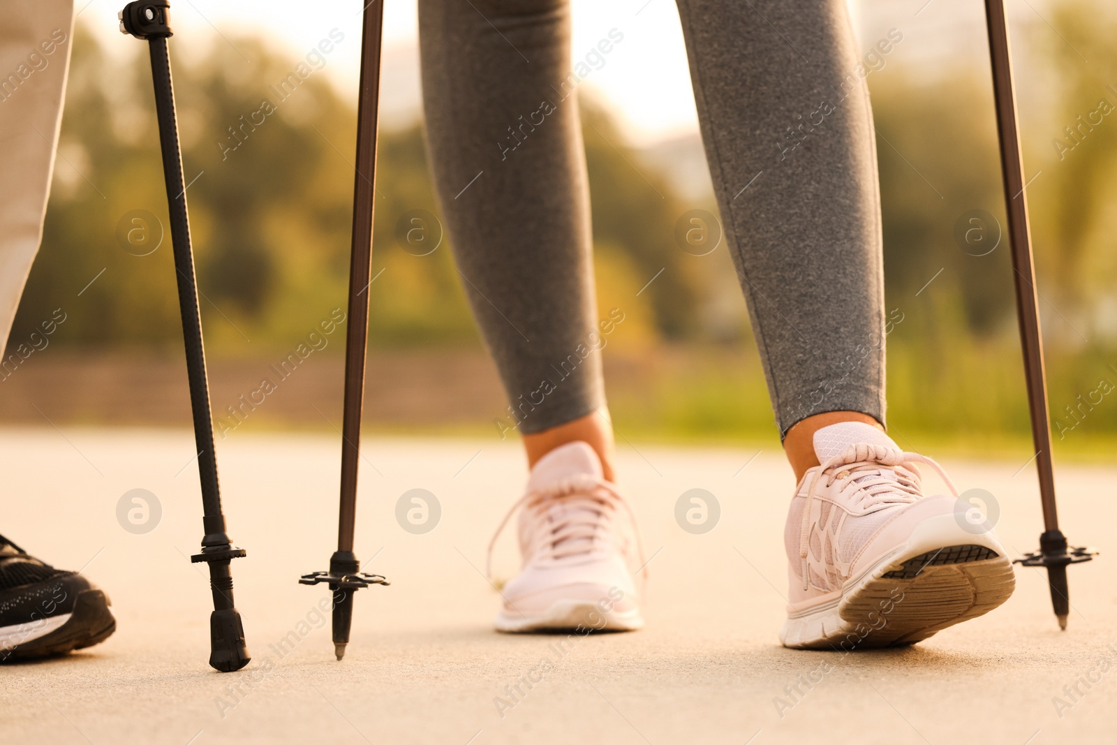 Photo of People performing Nordic walking outdoors, closeup view