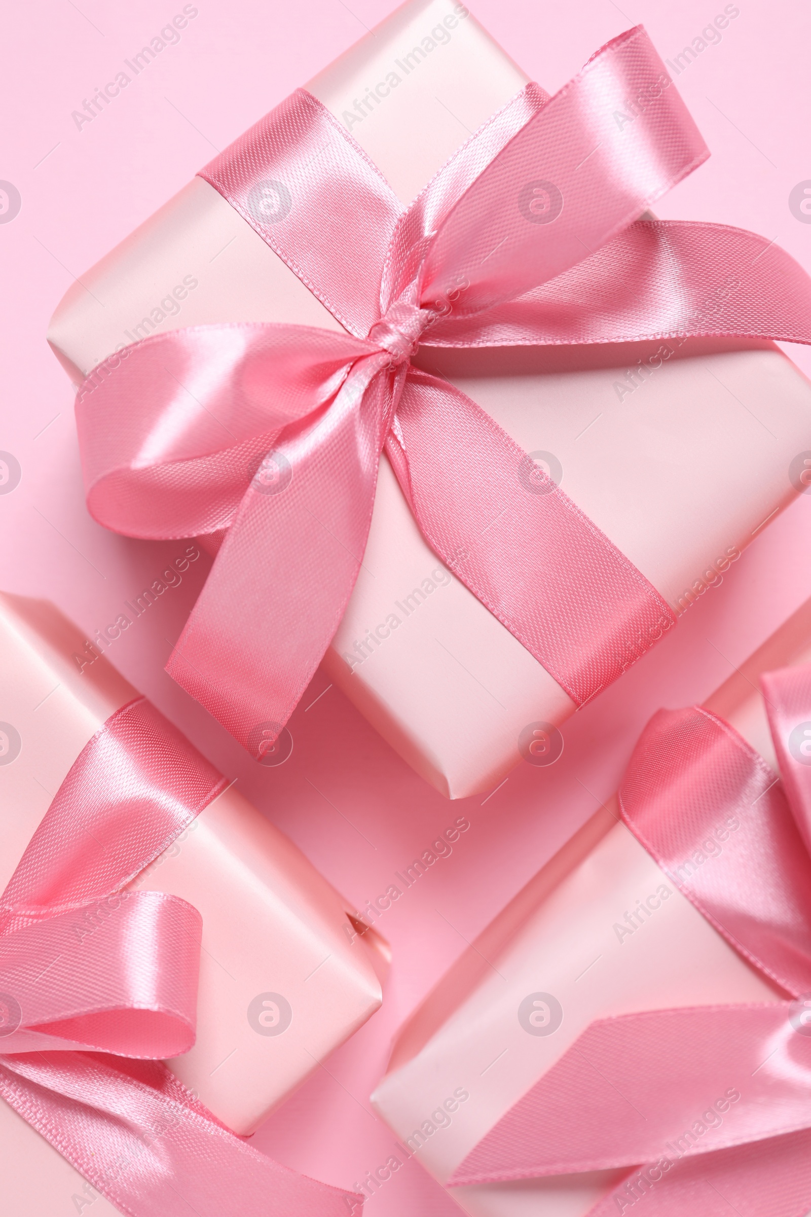 Photo of Beautiful gift boxes on pink background, flat lay