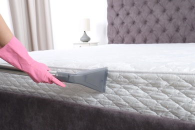 Photo of Woman disinfecting mattress with vacuum cleaner, closeup. Space for text