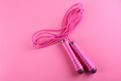 Photo of Skipping  rope on pink background, top view. Sports equipment