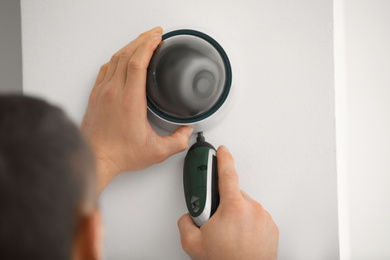 Technician installing CCTV camera on wall, closeup