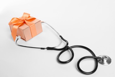 Photo of Stethoscope and gift box on white background. Happy Doctor's Day