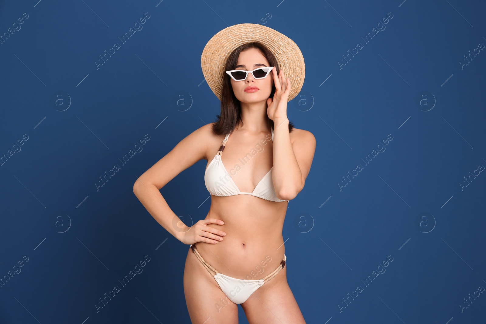 Photo of Beautiful woman in stylish bikini and sunglasses on blue background