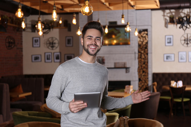 Young business owner with tablet in his cafe