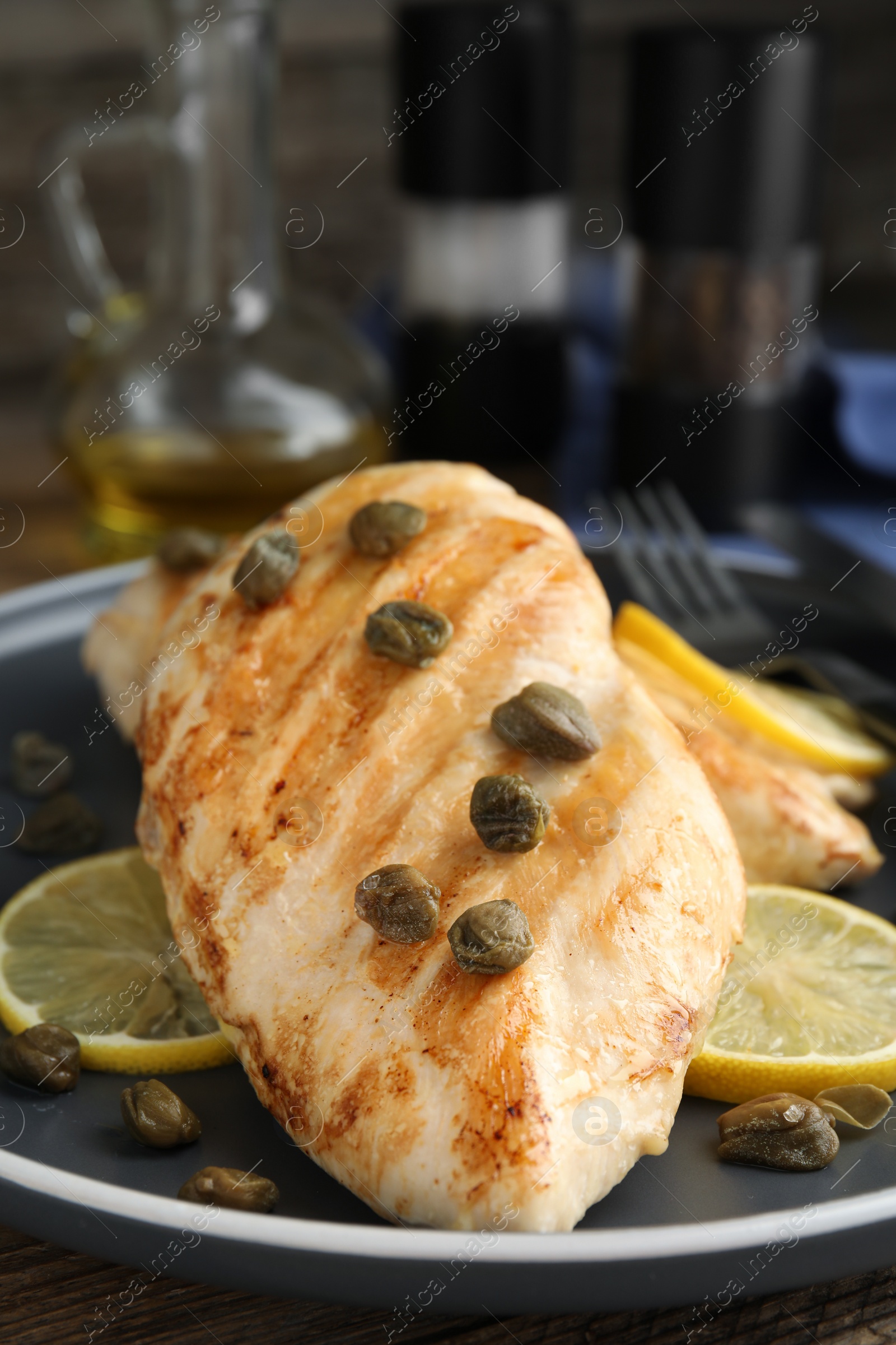 Photo of Delicious chicken fillets with capers and lemon on plate, closeup