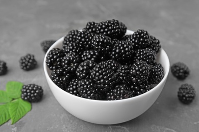 Photo of Bowl with tasty ripe blackberries on grey table