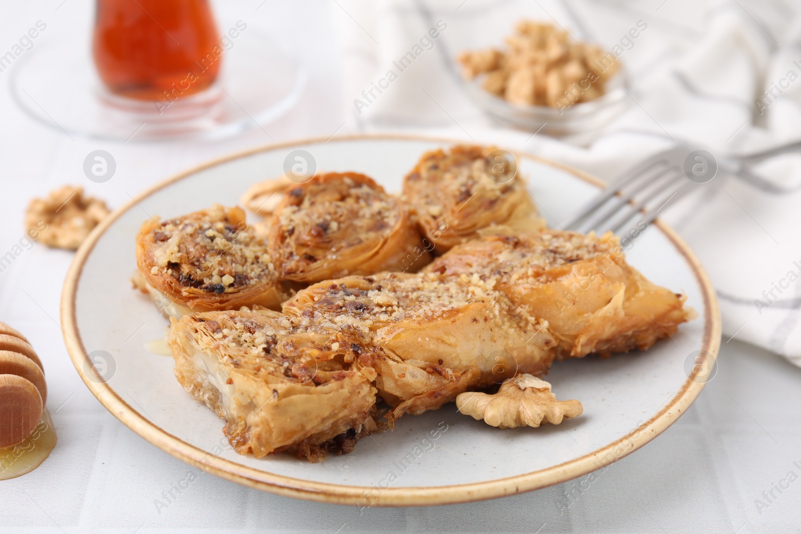 Photo of Eastern sweets. Pieces of tasty baklava on white tiled table, closeup