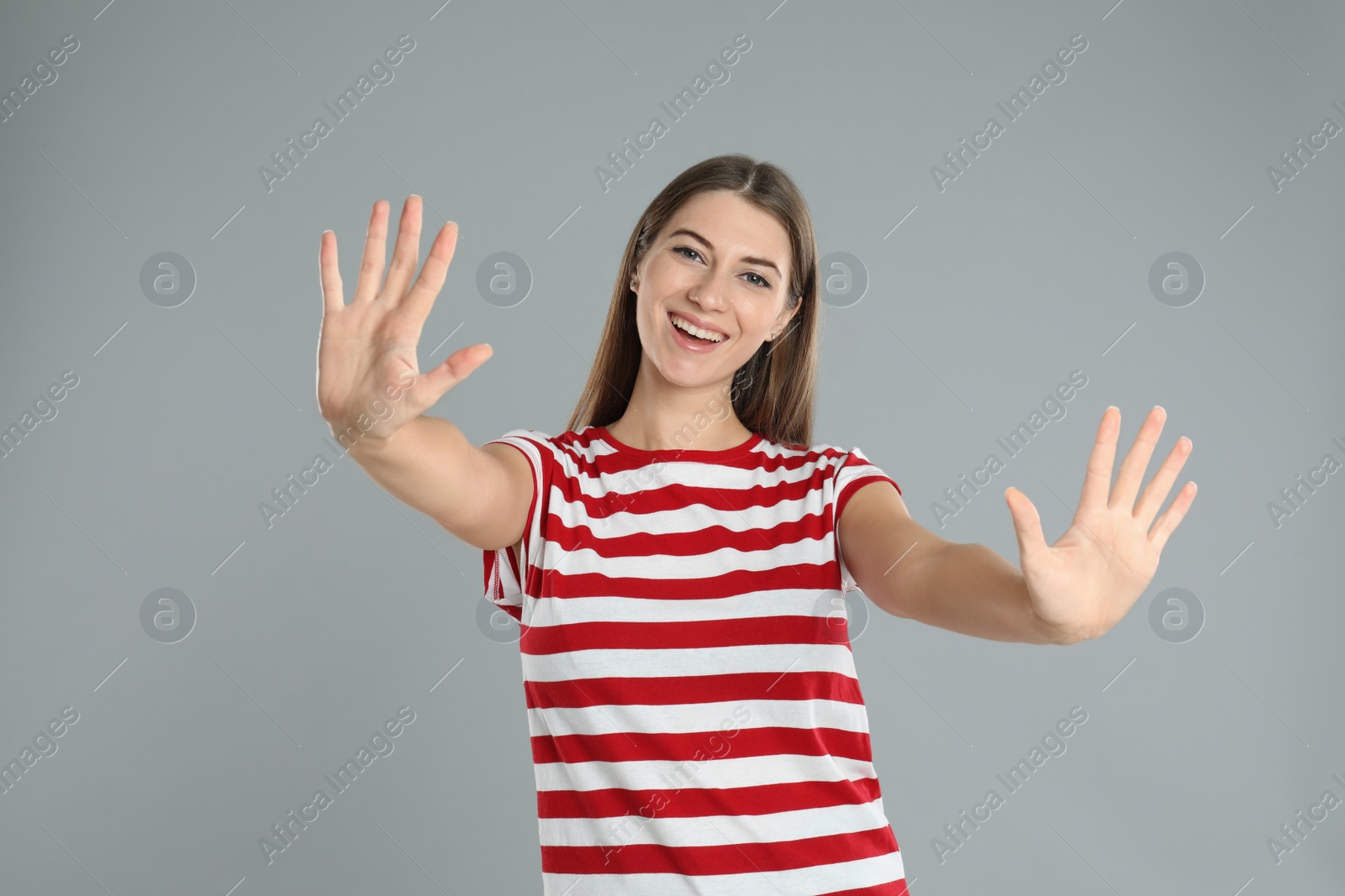 Photo of Woman showing number ten with her hands on grey background