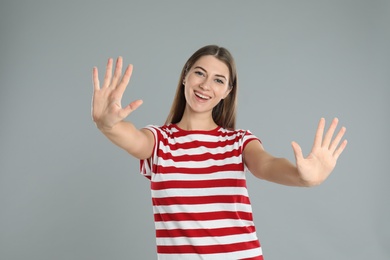 Photo of Woman showing number ten with her hands on grey background