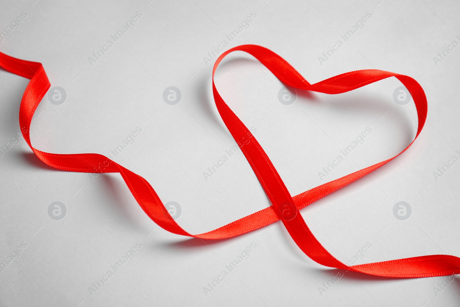 Photo of Heart made of red ribbon on light background