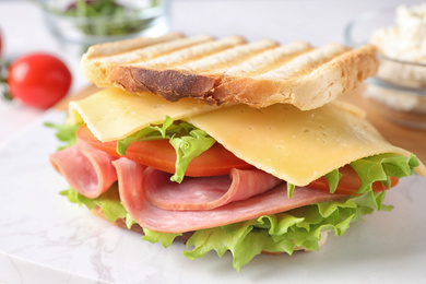 Photo of Tasty sandwich with ham on white marble table, closeup