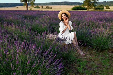 Photo of Beautiful young woman sitting in lavender field