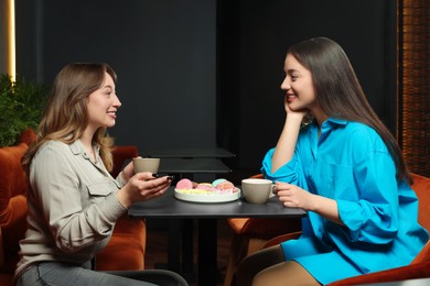 Photo of Young women with coffee spending time together in cafe