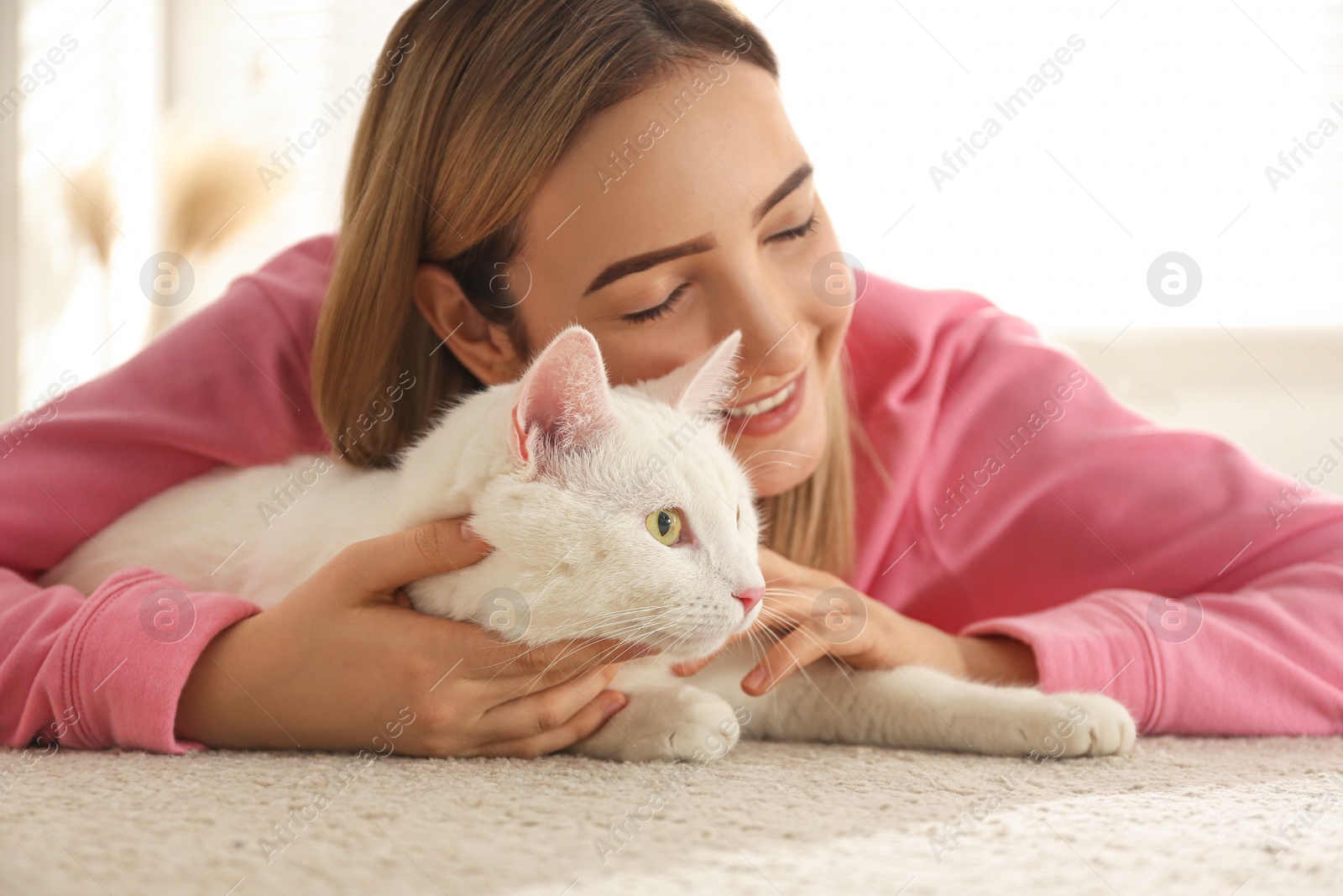 Photo of Young woman with her beautiful white cat at home. Fluffy pet