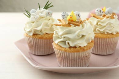 Tasty Easter cupcakes with vanilla cream on light wooden table, closeup