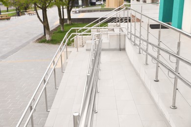 Photo of Tiled ramp with shiny metal railings outdoors