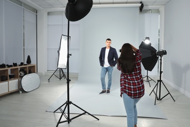 Photo of Professional photographer taking picture of young man in modern studio