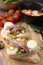 Photo of Delicious bruschettas with anchovies, eggs, cream cheese, tomatoes, bell peppers and cucumbers on table