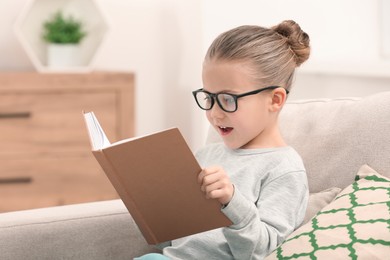 Photo of Portrait of cute little girl in glasses with book indoors