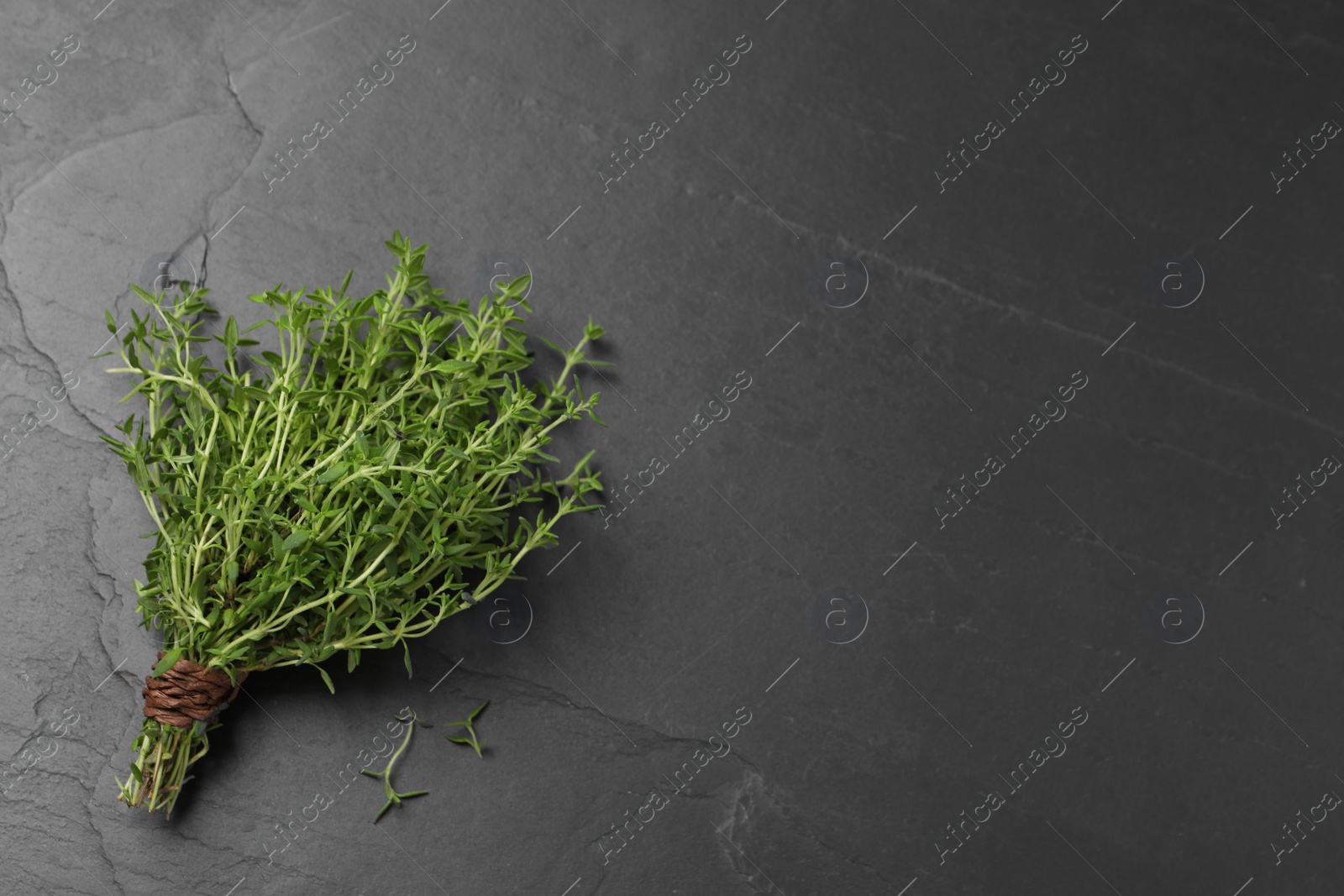 Photo of Bunch of aromatic thyme on black table, top view. Space for text