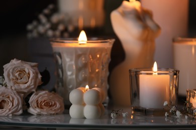 Beautiful burning candles and flowers on table