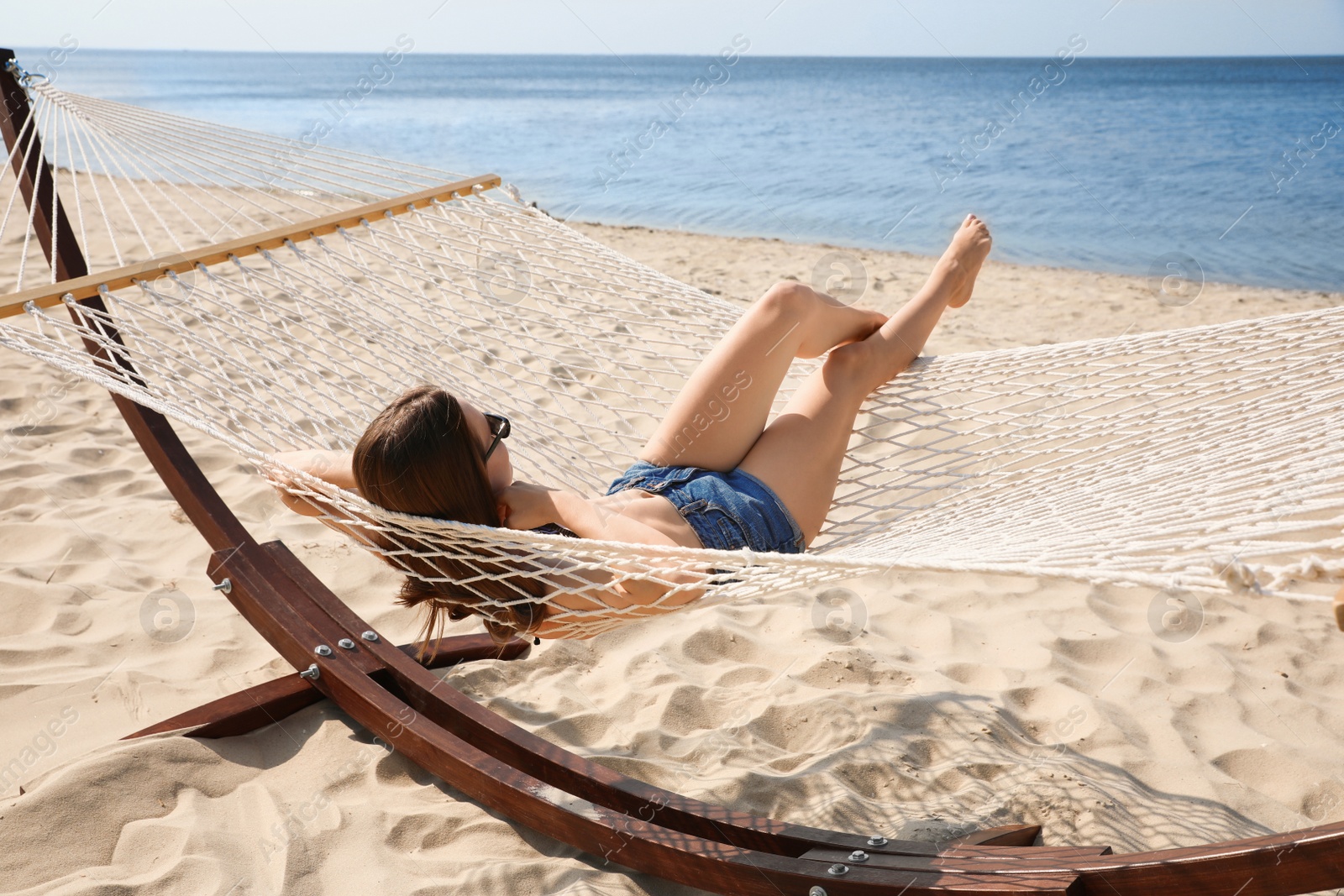 Photo of Young woman relaxing in hammock on beach