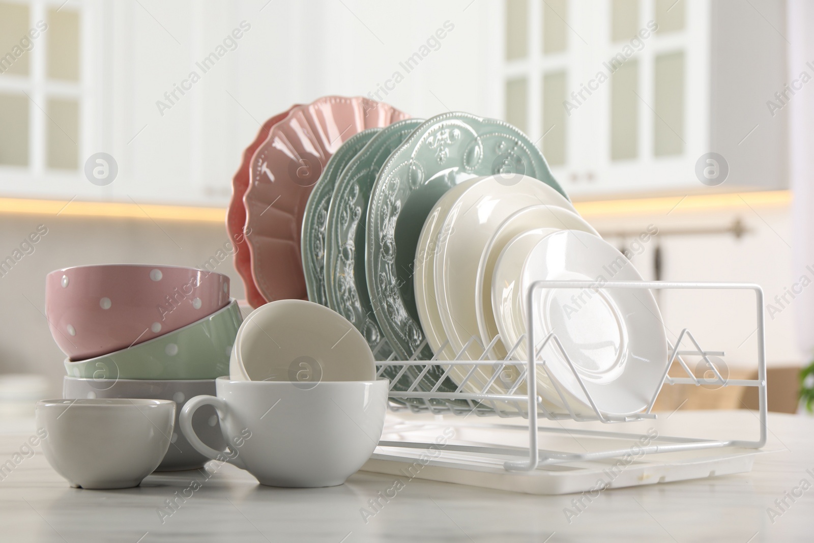 Photo of Many different clean dishware and cups on white marble table in kitchen