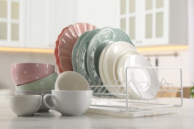 Many different clean dishware and cups on white marble table in kitchen