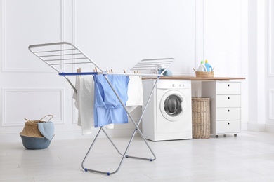 Clean laundry hanging on drying rack indoors