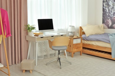 Photo of Stylish teenager's room interior with computer and comfortable bed