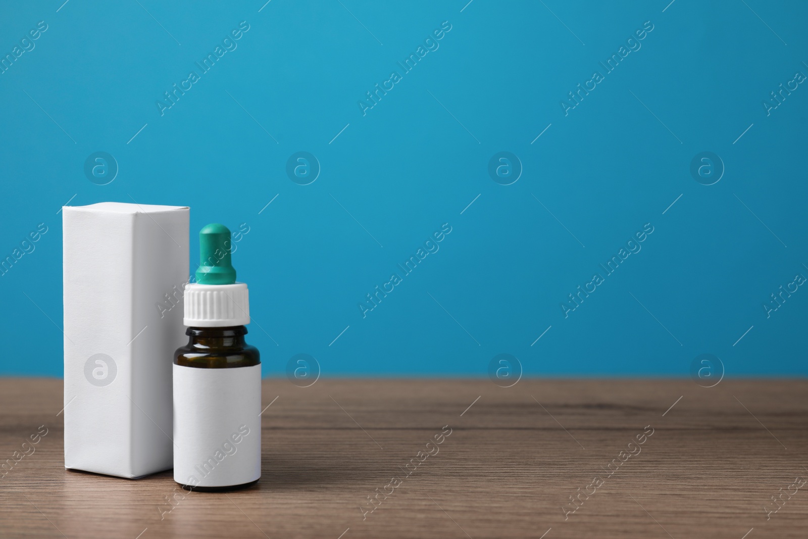 Photo of Nasal drops with blank label and package on wooden table against light blue background. Space for text
