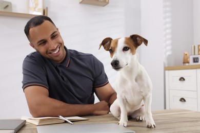 Photo of Young man with Jack Russell Terrier at desk in home office