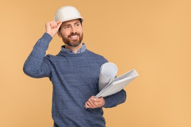 Photo of Architect in hard hat with draft and folder on beige background