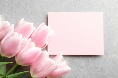 Photo of Beautiful tulips and card for Mother's Day on grey background, top view