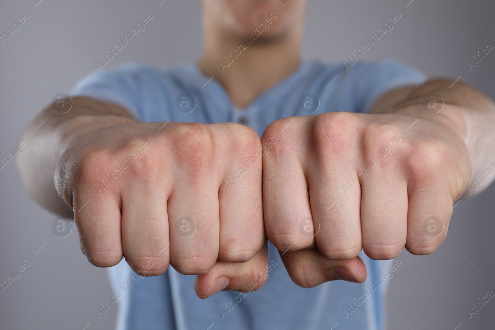 Photo of Man showing fists with space for tattoo on grey background, selective focus