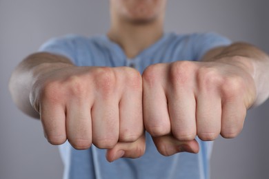 Photo of Man showing fists with space for tattoo on grey background, selective focus