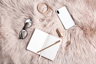 Photo of Flat lay composition with notebook, smartphone and stylish accessories on fur. Blogger concept