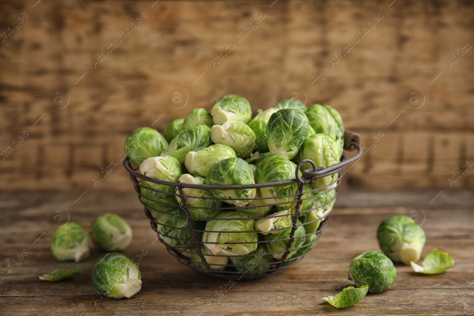 Photo of Metal basket with fresh Brussels sprouts on wooden table, closeup