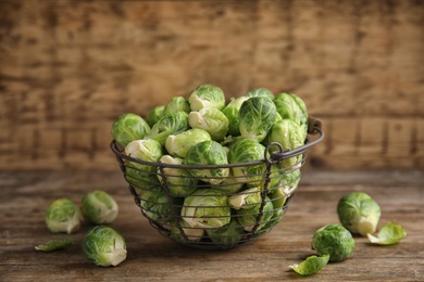 Metal basket with fresh Brussels sprouts on wooden table, closeup