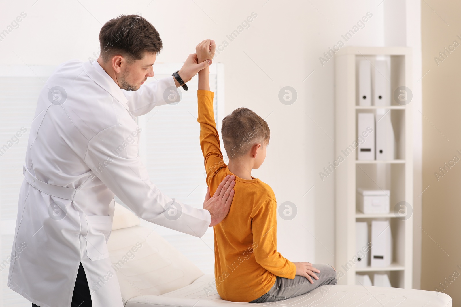 Photo of Chiropractor examining child with back pain in clinic