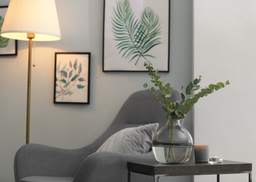 Photo of Vase with fresh eucalyptus branches on table in living room. Interior design