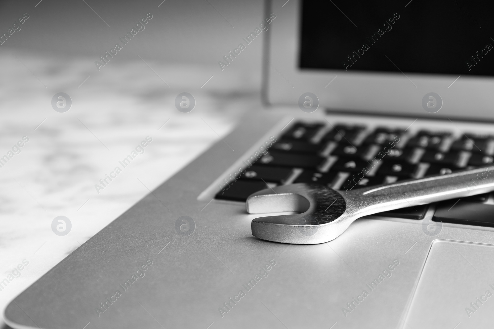 Photo of Laptop and spanner on table, closeup. Concept of technical support