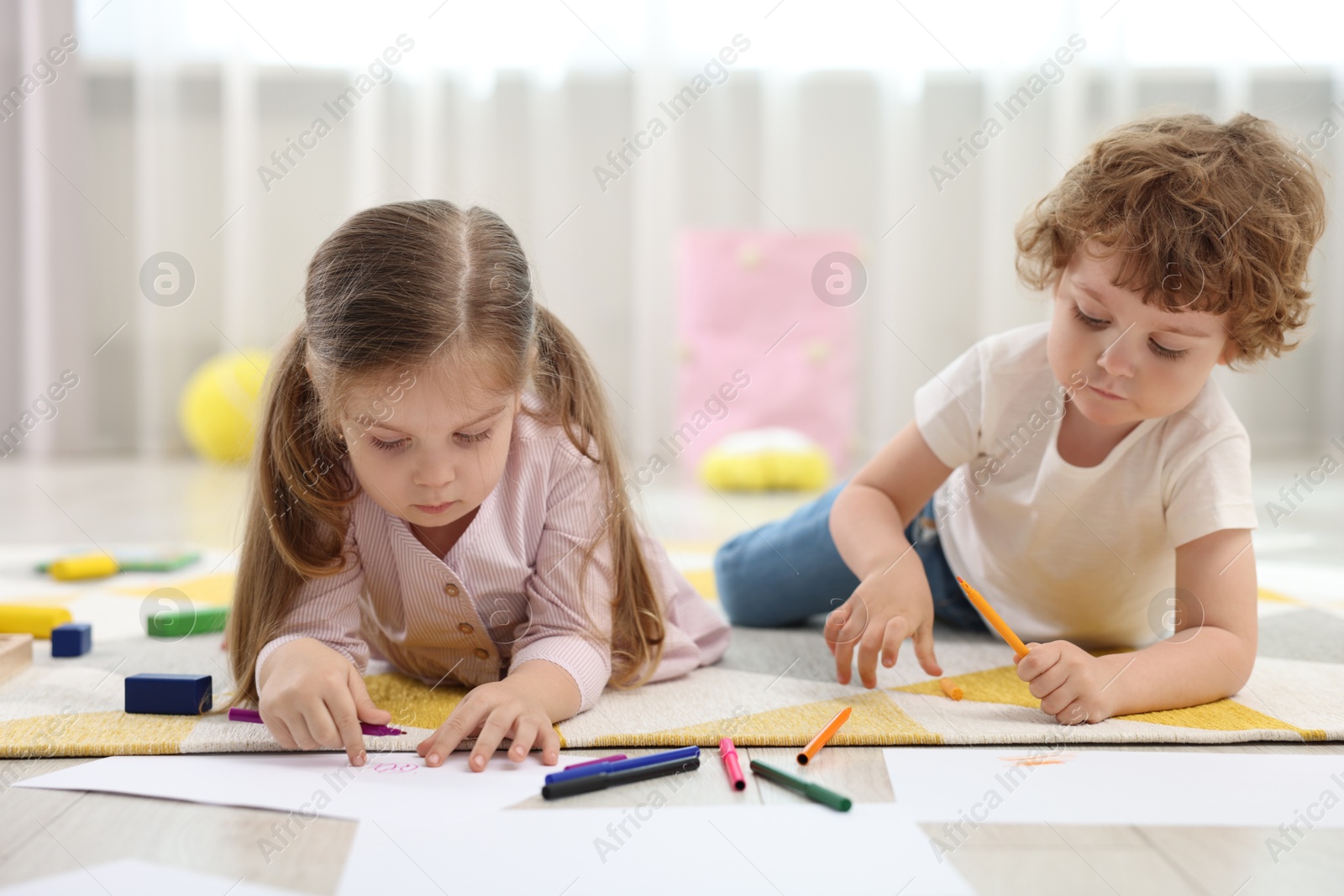 Photo of Cute little children drawing on floor in kindergarten