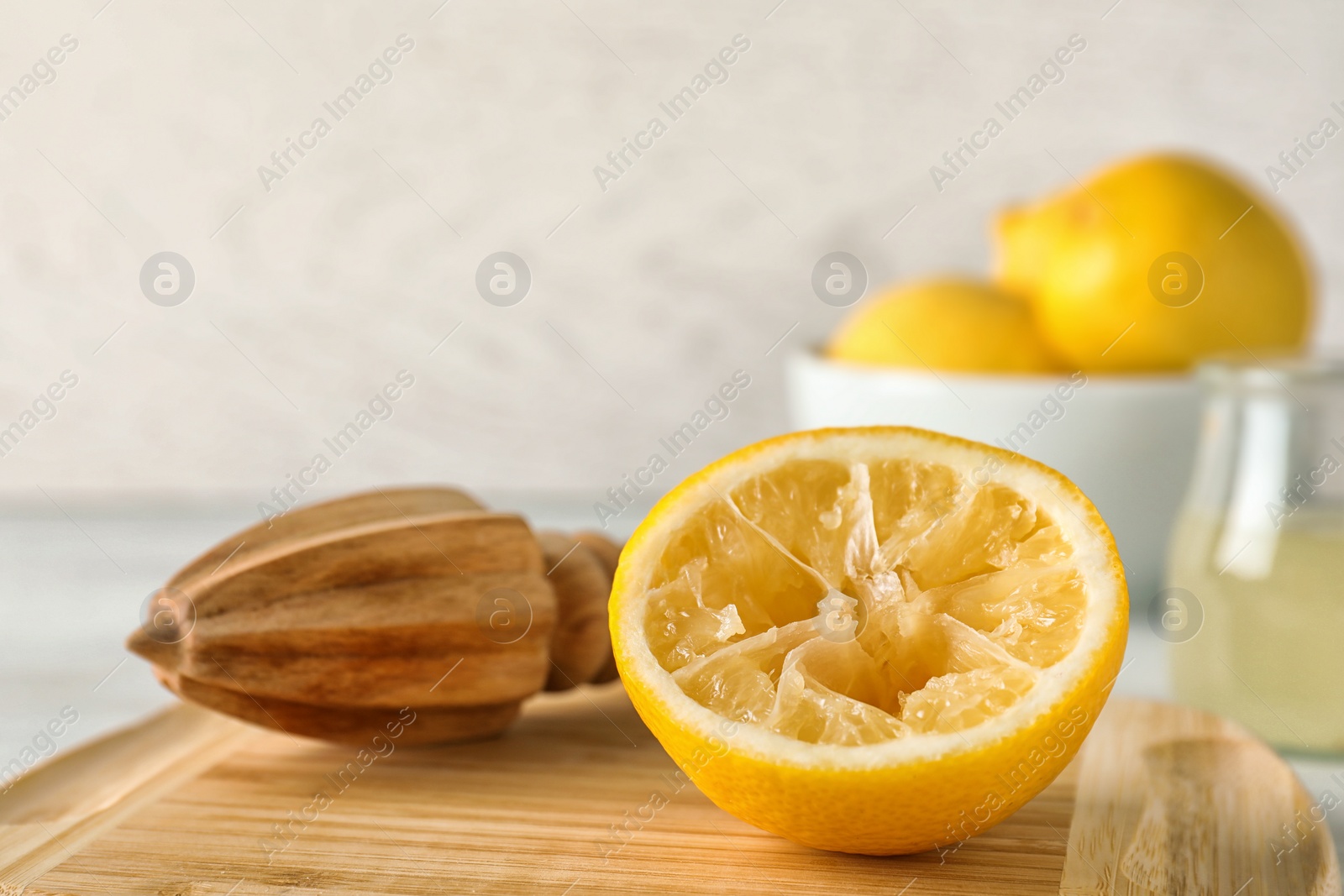 Photo of Wooden board with lemon reamer and squeezed fruit on table