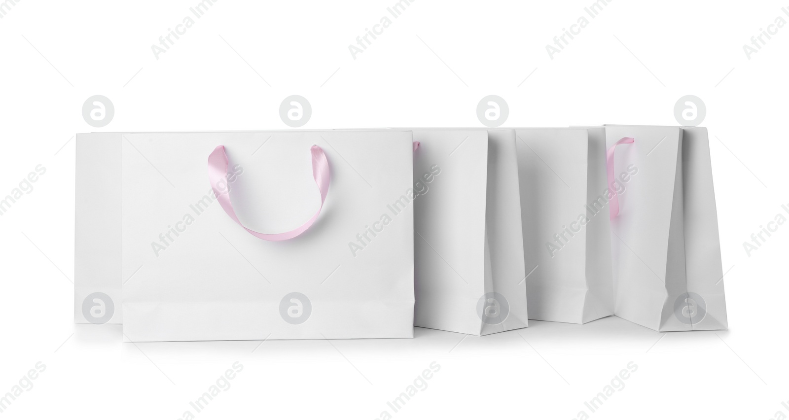 Photo of Paper shopping bags with ribbon handles on white background. Mockup for design