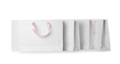 Photo of Paper shopping bags with ribbon handles on white background. Mockup for design