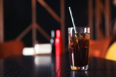 Photo of Glass of refreshing cola with ice on table indoors. Space for text