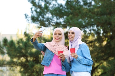 Muslim women in hijabs taking selfie outdoors